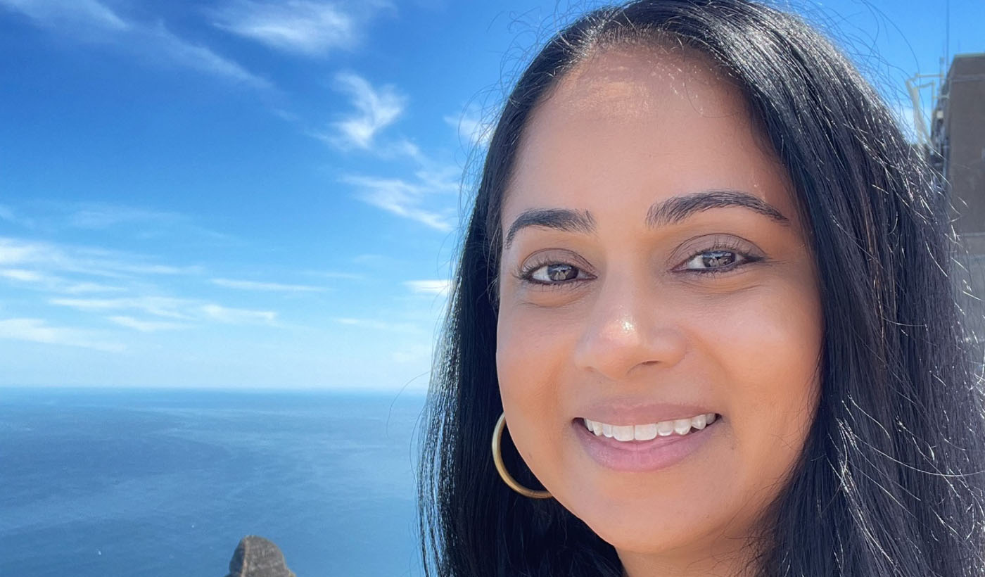 Una selfie de Rakhee sonriendo, con el océano detrás de ella.