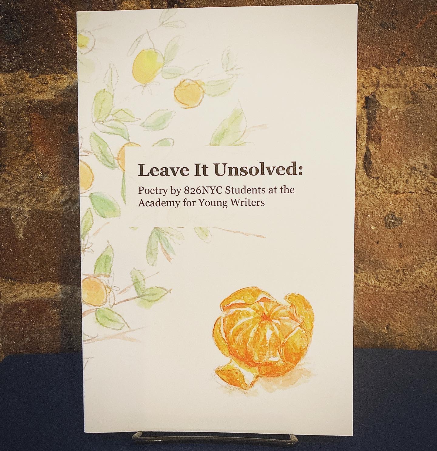 Leave It Unsolved - book cover with a mostly white background an a picture of a peeled orange in the foreground. Branches of an orange tree show behind the title text.