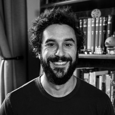 Black and white photo of the author Adam Rubin standing in front of a bookcase.