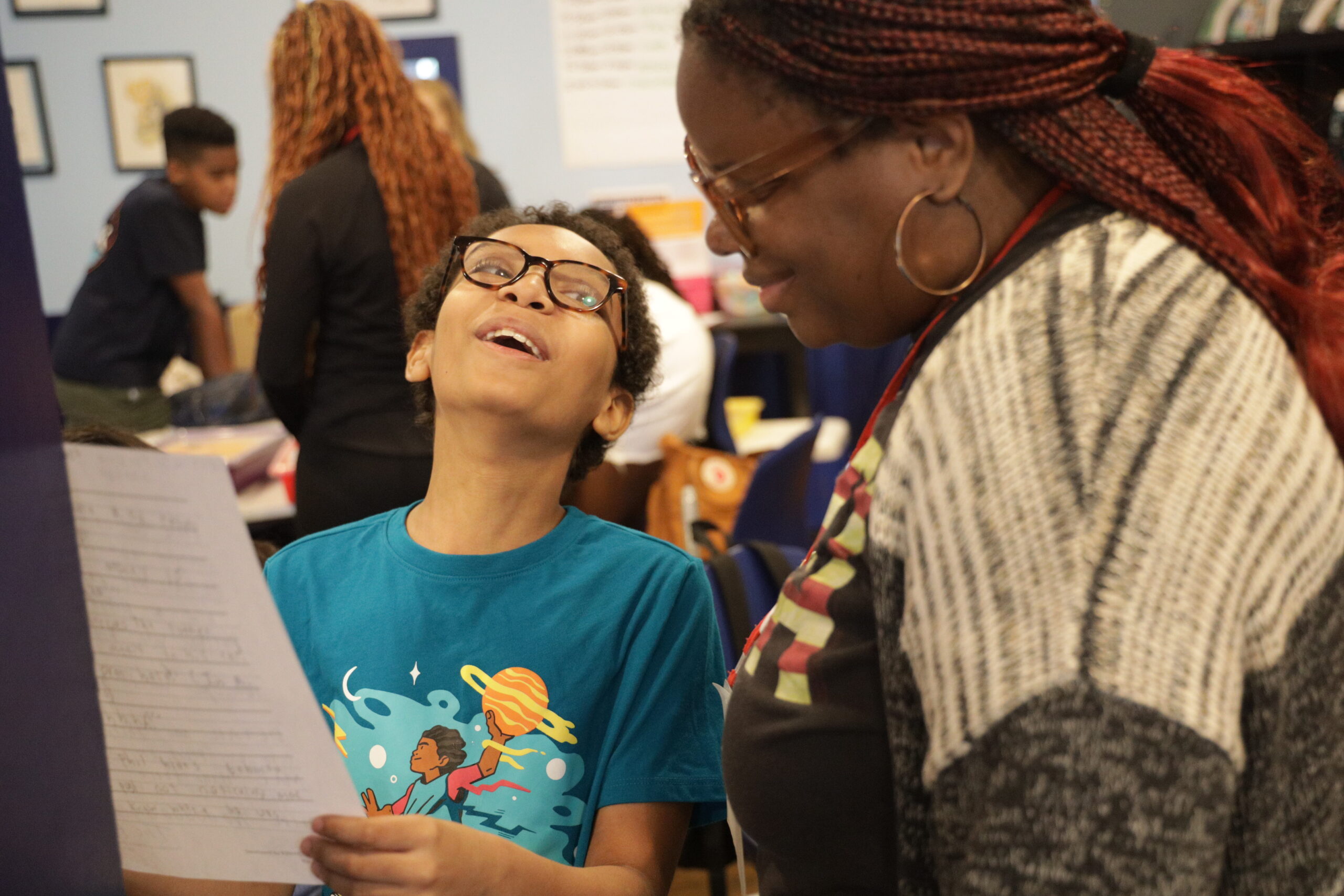 A student laughs as they read their story aloud to an 826NYC staff member.