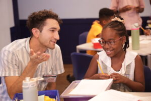A Write Away Workshop student and volunteer smile while talking together at the 826NYC secret library.